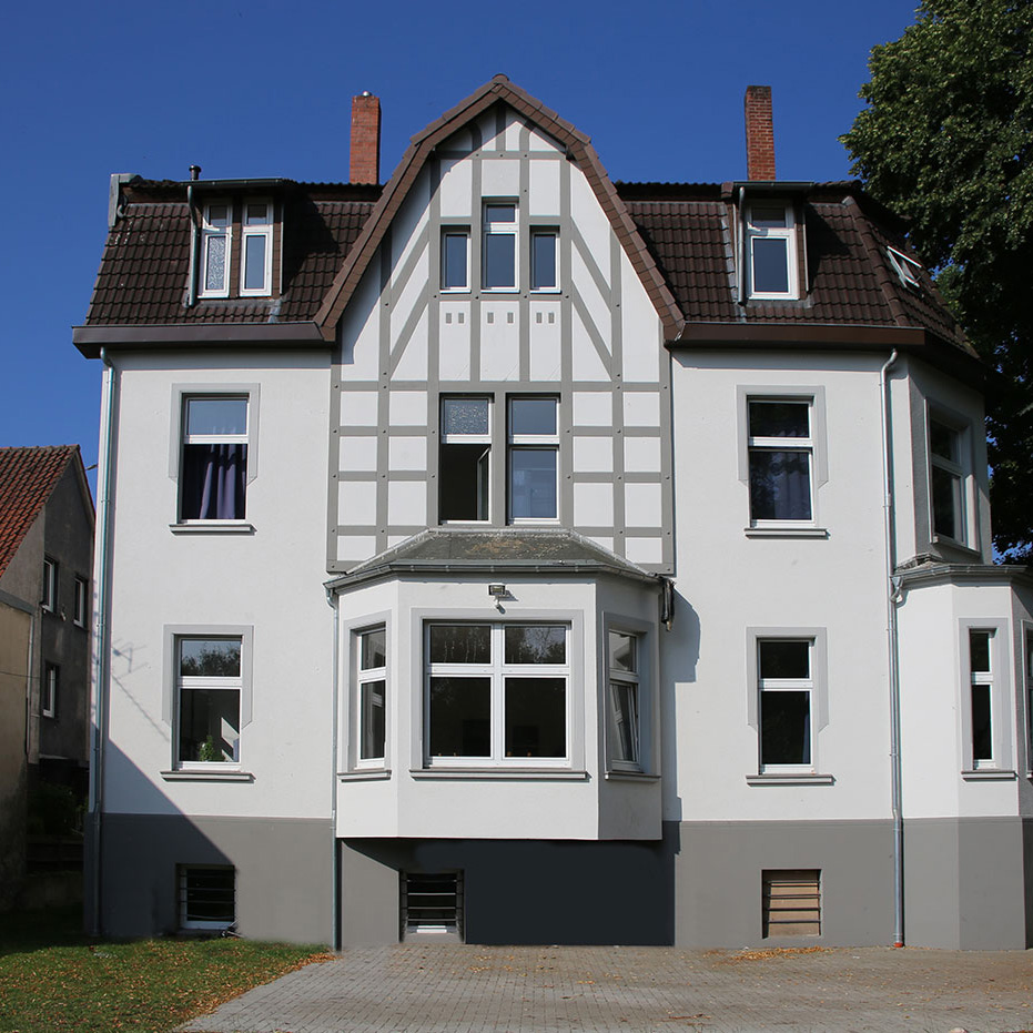 Fassade eines Mehrfamilienhauses mit Fachwerk-Elementen und mehreren Fenstern.