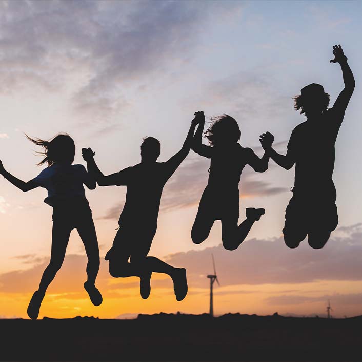 Gruppe von vier Personen, die zusammen in die Höhe springen.