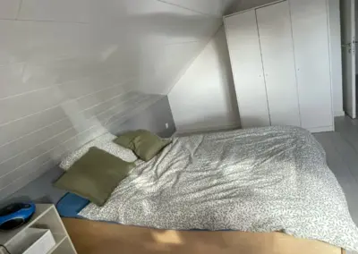 Ein Schlafzimmer mit einem Doppelbett, Kissen und einem Schrank an der Wand.