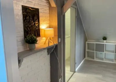 Innenansicht eines Raumes mit einer Lampe, einer Pflanze und einer Wanddekoration aus Metall.