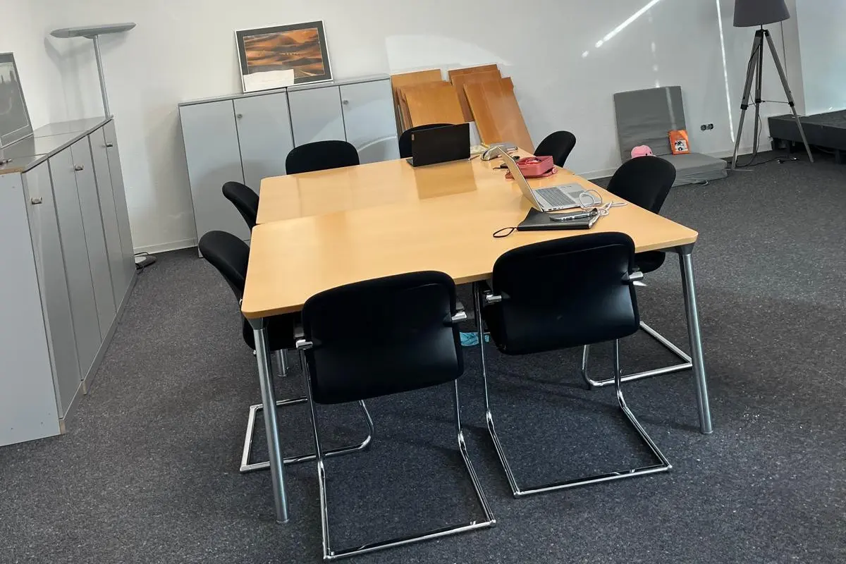 Heller Besprechungsraum mit Holztisch, schwarzen Stühlen und grauem Teppich; Bildrahmen an der Wand, Büroeinrichtung von Warstein im Neuanfang Kreis Warendorf