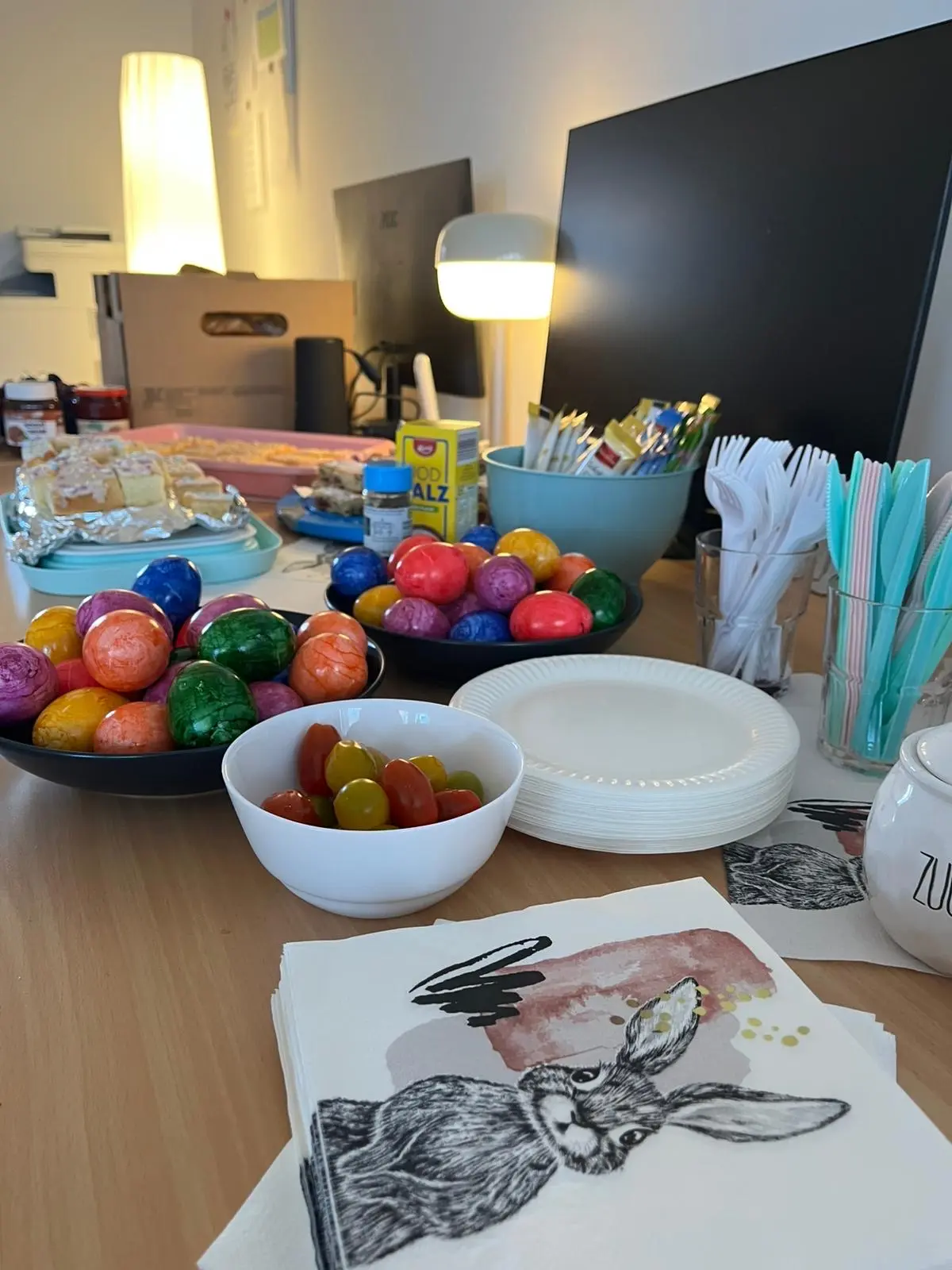 Bunt bemalte Ostereier in Schüsseln und Teller, daneben Malvorlage mit Hasenmotiv sowie bunte Eier zum kreativen Arbeiten bei Neuanfang gGmbH.