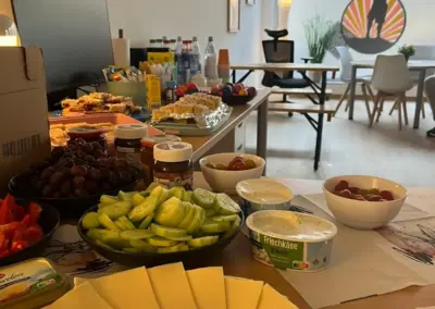 Osterangebot-Buffet mit Käse, Frischkäse Kräuter, Gemüsewürfeln, Oliven und Obst in Schalen sowie Osterdekoration im Raum